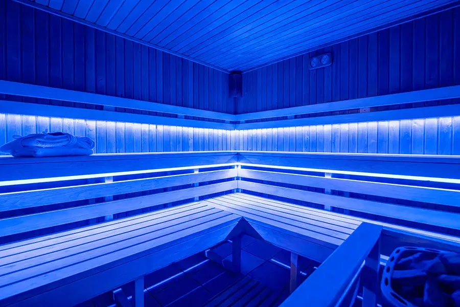 A Rubin Wellness & Conference Hotel Budapest bio szaunája kék LED világítással, ahol fa padok és fa mennyezet látható relaxáló hangulatban