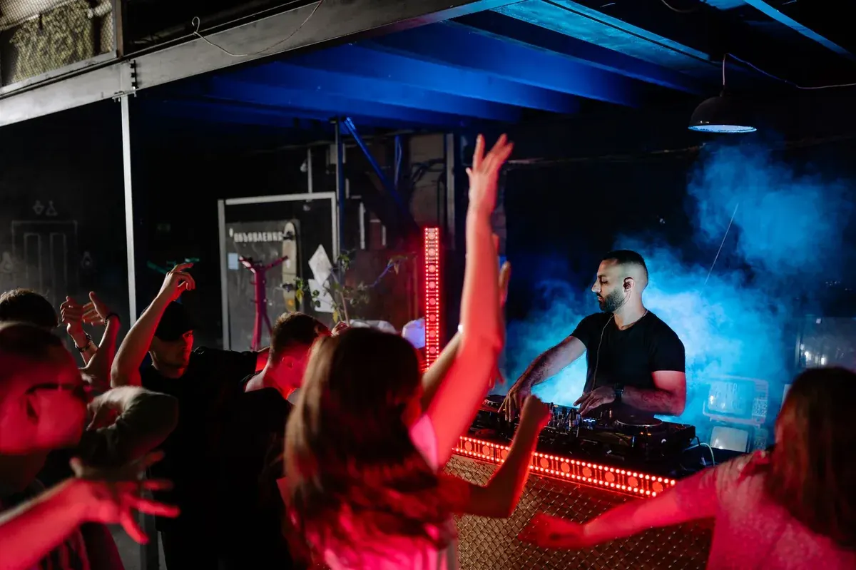 DJ és táncoló tömeg színes fényekben egy céges partin